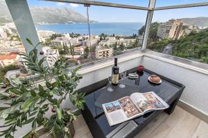 a table with a bottle of wine and a book on a balcony at Apartment 4You in Budva