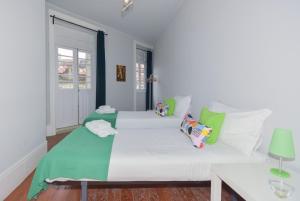 a bedroom with a large white bed with green pillows at Oporto Rivoli Apartments in Porto