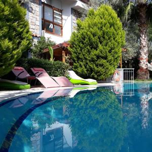 a swimming pool with blue water and trees at Jasmin Apart Otel in Göcek