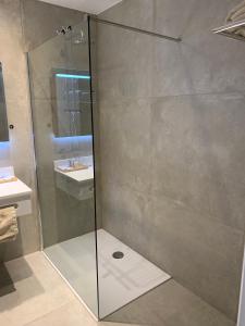 een douche met een glazen deur in de badkamer bij Hotel Arcato in De Haan
