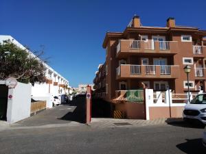 a building with cars parked in front of a street at Casa Luisa in Caleta De Fuste