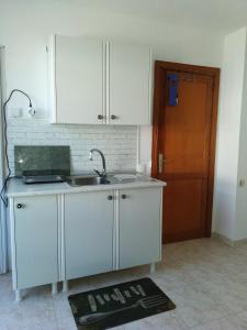 cocina con armarios blancos, fregadero y puerta en Casa Luisa, en Caleta de Fuste