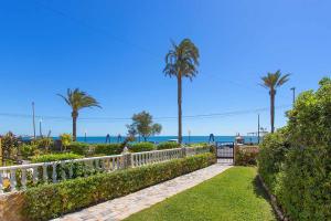 ogród z palmami i oceanem w tle w obiekcie CH Vista Alegre Rocio del Mar w mieście Torrevieja