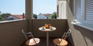 - Balcón con mesa pequeña y 2 sillas en Villa Dalmatia Apartments, en Bol