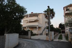 a building with a palm tree in front of a street at Apartments Demarin in Medulin