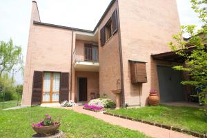 a brick house with a porch and a yard at La villetta d' angolo in Migliarino