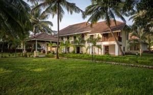 une maison avec des palmiers en face d'une cour dans l'établissement The Postcard Cuelim, Goa, à Cansaulim