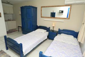 two beds in a room with blue cabinets and a mirror at Nemo Studios in Polykhrono