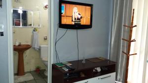 a bathroom with a tv on a wall with a television on it at Suíte Fiore Ponta Verde in Maceió