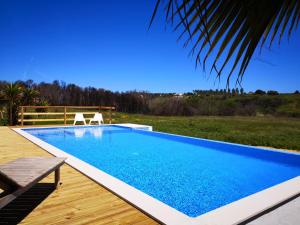 a swimming pool with a wooden deck and a blue pool at Quinta de Moledos in Aljezur