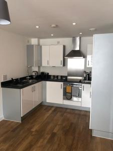 a kitchen with white cabinets and black counter tops at Quayside Apartment in Cardiff Bay in Cardiff