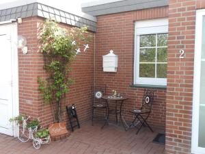 a brick wall with a patio with a table and chairs at Ferienhaus Menkhoff in Dornumersiel