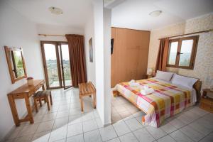 a bedroom with a bed and a desk and window at Irene Komos in Pitsidia