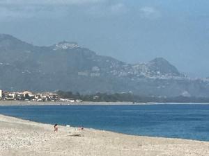 a group of people on a beach with mountains in the background at Casa Vacanze Samira in Fondachello