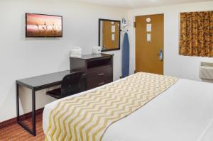 ein Hotelzimmer mit einem Bett und einem Schreibtisch in der Unterkunft Travelodge by Wyndham Manhasset in Manhasset