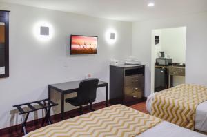 a hotel room with two beds and a desk at Travelodge by Wyndham Manhasset in Manhasset