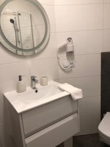 La salle de bains est pourvue d'un lavabo blanc et d'un miroir. dans l'établissement Willa Biały Dom, à Białogóra