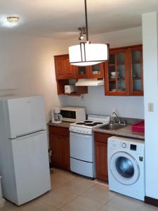 a kitchen with a white refrigerator and a dishwasher at Point Village Negril in Negril