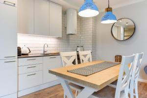 kuchnia z drewnianym stołem i białymi szafkami w obiekcie Naviflat- Luxury Sopot Residence Okrzei 21 by Lion Apartments w mieście Sopot +3 zdjęcia
