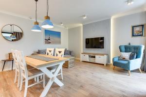 jadalnia ze stołem i krzesłami oraz telewizorem w obiekcie Naviflat- Luxury Sopot Residence Okrzei 21 by Lion Apartments w mieście Sopot
