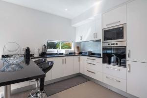 une cuisine avec des placards blancs et un comptoir noir dans l'établissement Apartamento Pita by HR Madeira, à Funchal