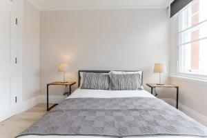 een witte slaapkamer met een groot bed met 2 lampen bij StayInn Farringdon in Londen