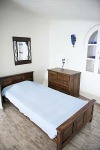 a bedroom with a bed and a dresser and a mirror at Captain John Houses Caldera Oia in Oia