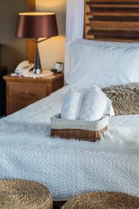 uma cama com lençóis brancos e almofadas em Pousada Rabo do Lagarto em Pedra Azul