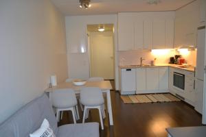 cocina con armarios blancos, mesa y sillas en Galaxy Apartments Airport en Vantaa