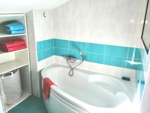 La salle de bains est pourvue d'une baignoire et de carrelage bleu et blanc. dans l'établissement Les Toits du Capitole - Loft de standing 60 m2 - Parking en option, à Toulouse