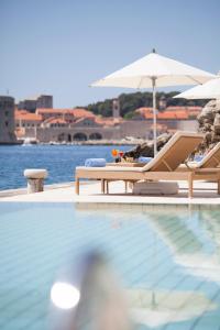 a beach scene with a pool and a chair at Grand Villa Argentina in Dubrovnik