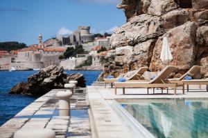 een zwembad met ligstoelen naast het water bij Grand Villa Argentina in Dubrovnik