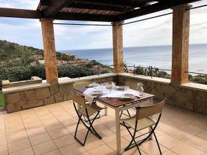 uma mesa e cadeiras num pátio com vista para o oceano em Casa Porto Corallo em Villaputzu