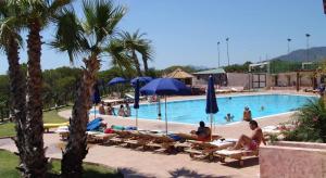 a group of people sitting in chairs at a swimming pool at Casa Porto Corallo in Villaputzu