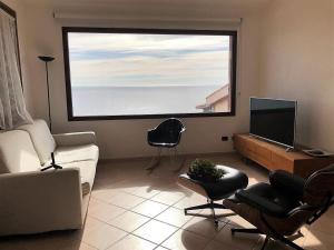 uma sala de estar com um sofá e uma grande janela em Casa Porto Corallo em Villaputzu