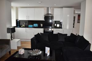 a living room with a black couch and a kitchen at Luxlogic in London