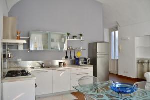 een keuken met witte kasten en een glazen tafel bij La mia casa in Biella