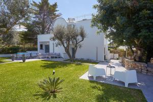 um quintal com duas cadeiras brancas e uma casa em Casa del Melograno con idromassaggio e giardino em Terrasini