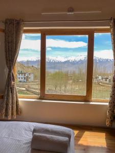 a bedroom with a window with a view of mountains at Heschuk Guest House in Leh