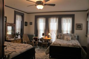 a bedroom with a bed and a desk and a ceiling fan at Spencer House Bed & Breakfast in Erie