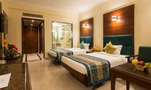 a hotel room with two beds and a table at Shenbaga Hotel And Convention Centre in Pondicherry