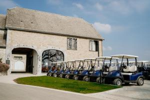 um grupo de carrinhos de golfe estacionados em frente a um edifício em Hôtel Five Nations em Durbuy