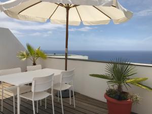 a white table and chairs on a balcony with an umbrella at Apartamento Atico Guanchita in Tazacorte