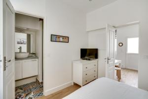 a white bedroom with a sink and a television at Apartment 3 people close Eiffel Tower by Weekome in Paris