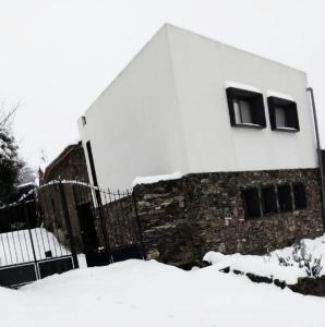 a building with snow on the ground next to a fence at Casa D'o Canto in Vinhais