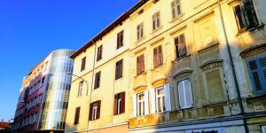 a yellow building with windows and a glass building at Pula Center Apartments and Rooms in Pula