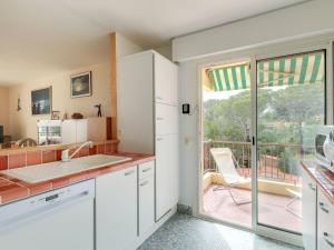 a kitchen with white cabinets and a view of a balcony at Apartment Boulouris Mimosa by Interhome in Saint-Raphaël