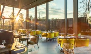 un restaurante con mesas, sillas amarillas y ventanas en Olympic Hotel en Ámsterdam