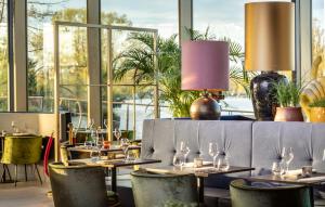 a restaurant with tables and chairs and large windows at Olympic Hotel in Amsterdam