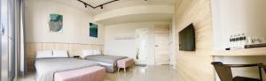 een hotelkamer met 2 bedden en een televisie bij C.C. Sleep in Magong